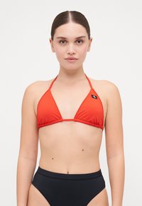Röd bikiniöverdel med triangulära kupa och tunna band, med en logotypklack. Bärs med högmidjade svarta bikiniunderdelar.