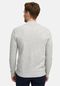 Maglione grigio a maglia con colletto tondo, polsini e orlo a coste. Il retro presenta una texture liscia e una lunghezza leggermente più lunga.