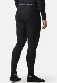 Black ribbed leggings featuring a wide waistband with "SWEDEMOUNT" label, fitted silhouette, and seamless texture. Worn with black socks.