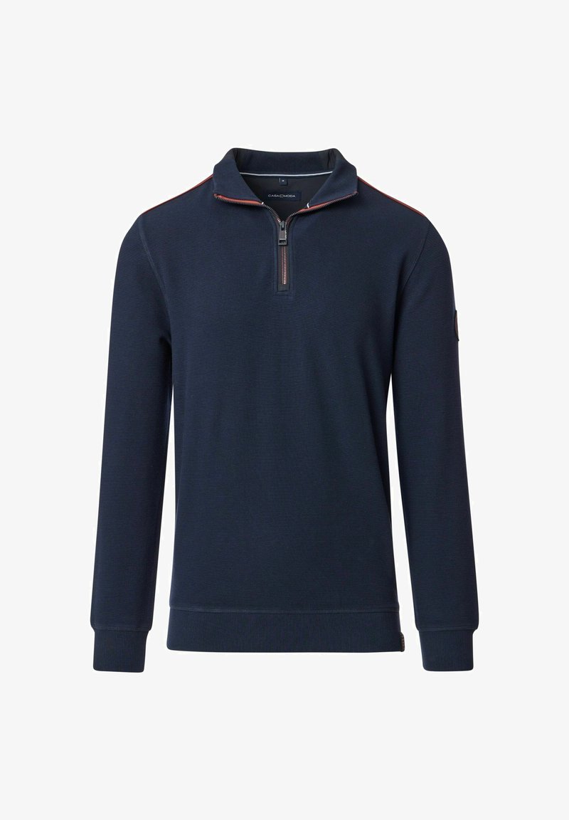 Granatowy sweter z kołnierzem na pół-zamek, faktura ribbed, z kontrastowymi czerwonymi szwami wzdłuż zamka. Posiada długie rękawy i naszywkę z logo.