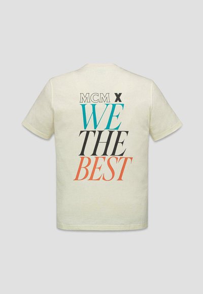 T-shirt beige à manches courtes avec un grand texte multicolore dans le dos indiquant "MCM X WE THE BEST."
