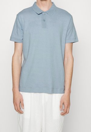 Polo di cotone azzurro chiaro con colletto strutturato, abbottonatura a due bottoni e maniche corte, caratterizzata da una vestibilità comoda e dettagli sull'orlo.