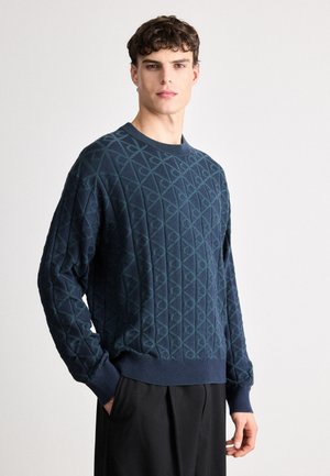 Navy blue knitted sweater featuring a textured diamond pattern, ribbed crew neckline, and long sleeves with fitted cuffs.