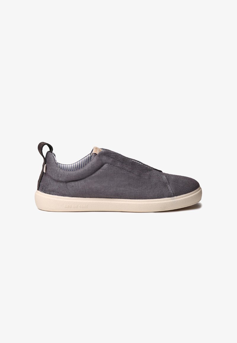 Καθημερινό γκρι παπούτσι slip-on με λευκή σόλα, υφασμάτινο πάνω μέρος, θηλιά στο πίσω μέρος και ριγωτή εσωτερική επένδυση.