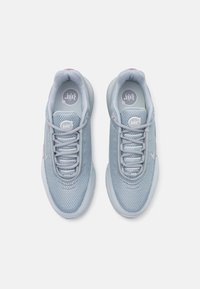 Light blue athletic shoes with a mesh upper, rounded toe, and textured tongue featuring pink accents and a circular logo on the insole.