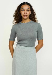 Top gri ajustat cu mânecă scurtă și decolteu rotund, asortat cu o fustă gri deschis. Materialul pare moale și elastic, potrivit pentru ținute casual.