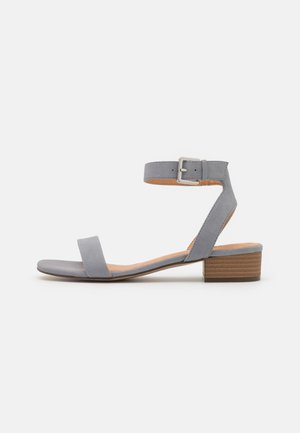 Sandale en cuir gris avec bride à la cheville, bande avant plate et petit talon carré. Boucle réglable pour un ajustement parfait, texture lisse, design simple.