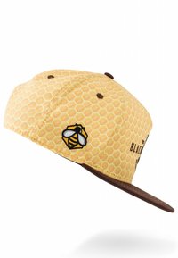 Kollane snapback müts, millel on mesitaru mustriga kangas, pruun visor ja tikandiga mesilase logo küljel, tooni tekstuuriga kangas.