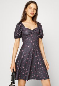 Vestido floral escuro com mangas bufantes, decote quadrado e corpete franzido. Apresenta pequenas flores rosas e brancas sobre um fundo escuro.