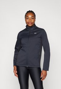Črna zip-up jakna, mehka tkanina, visok ovratnik, stranska žepa, prilegajoča zasnova, vsebuje subtilen logotip na prsih, gladka tekstura.
