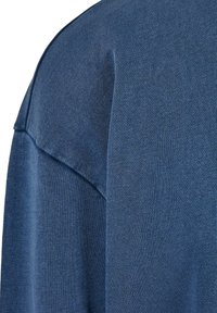 Pullover blu scuro con una trama a coste, dotato di un design con sovrapposizione sulle spalle e una finitura liscia, che mette in risalto il suo tessuto morbido.