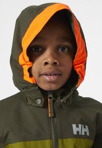 Groene waterdichte jas met een oranje capuchonvoering, voorzien van een ritssluiting aan de voorkant, knopen en een contrasterende gele streep over de borst.
