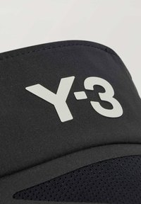 Czarna czapka z tkaniny z białym logo "Y-3", o gładkiej fakturze i zakrzywionym daszku. Siatka wewnątrz zapewnia wentylację.