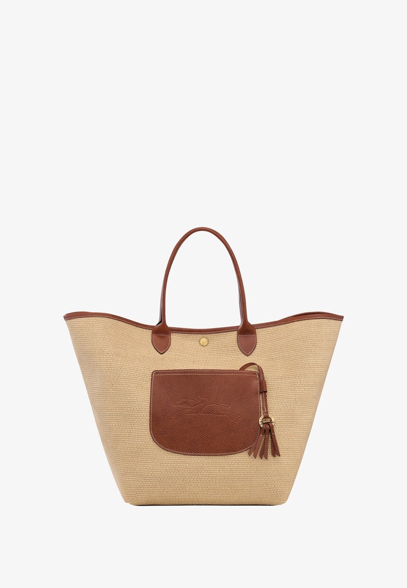 Tan woven tote bag with brown leather accents, large main compartment, and a front pocket featuring a decorative tassel.