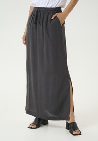 Gonna maxi in lino grigia con una vita elastica, cordoncino regolabile, spacchi laterali e tasche, abbinata a scarpe con tacco a blocco aperte nere.