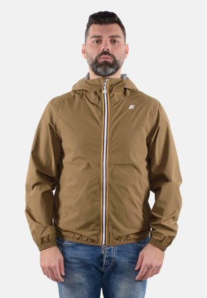 Giacca leggera marrone con zip frontale, polsini elastici e cappuccio. Presenta una striscia colorata lungo la zip e un logo sul petto.