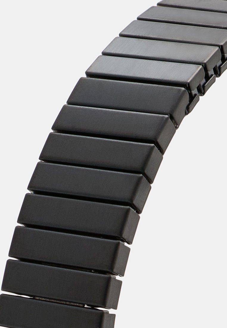 Pulsera elástica negra hecha de segmentos rectangulares planos, con una textura suave y forma uniforme con un acabado mate.