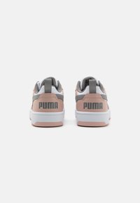Sneakers PUMA con una toma superiore in materiale sintetico rosa, dettagli grigi e suola in gomma bianca. Include elementi brandizzati sul tallone e linguette per indossarle facilmente.