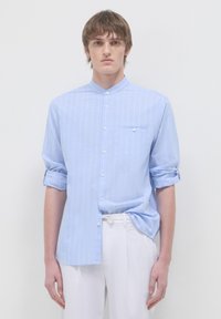 Camicia a maniche lunghe blu chiaro con sottili righe bianche verticali, colletto con bottoni, taschino sul petto, maniche arrotolate e tessuto liscio.