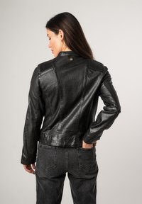 Schwarze Leder-Motorradjacke mit gerippten Akzenten, strukturierten Schultern und einer taillierten Passform. Detaillierte Nähte und ein Knopfverschluss am Kragen.