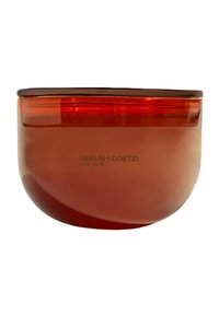 Bernsteinfarbener Glas-Teelichthalter mit einer glatten, runden Form. Verfügt über einen dunklen Rand und einen aufgedruckten Markennamen auf der Vorderseite.