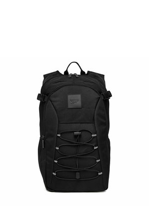 Schwarzer Reebok-Rucksack mit elastischem Frontkordelzug, mehreren Reißverschlussfächern und Tragegriff oben vor weißem Hintergrund.