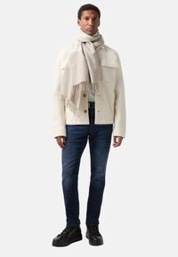 Weiße Wolle-Mischung Jacke mit zwei Fronttaschen, kombiniert mit dunkelblauen Denim-Jeans, einem hellbeigen Schal und schwarzen Schnürschuhen.