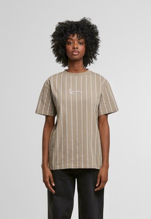Tan short-sleeve t-shirt featuring white vertical stripes and a signature graphic on the chest. Made from a smooth, cotton-like material.