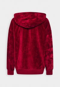 Felpa rossa in velluto con una texture morbida, maniche lunghe e cappuccio con cordino. L'orlo inferiore e i polsini sono a coste per una vestibilità migliore.