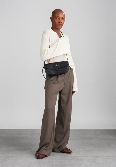 Black leather crossbody bag with a flap closure and gold accent. Paired with a cream ribbed sweater and brown wide-leg trousers.