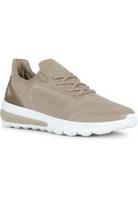 Beige stickad sneaker med en texturerad mesh-överdel, rund tå och vit gummisula med en distinkt vävd detalj på mellansulan.