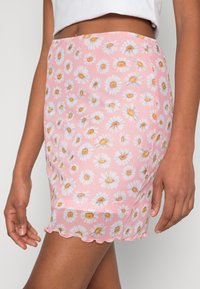 Mini-jupe florale rose avec un motif de marguerite, en tissu doux, ourlet festonné et silhouette ajustée.