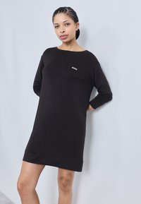 Black pullover dress with a round neckline and long sleeves. Features a small white "BOSS" logo on the chest. Soft, stretchy fabric.
