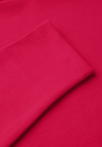 Tejido de ribete fucsia que presenta una textura suave, con un puño doblado que muestra una costura ordenada a lo largo del borde.