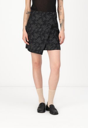 Svart omslagsskjørt med et teksturert blomstermønster med hvite detaljer. Stylet med lyse sokker og svarte loafers.