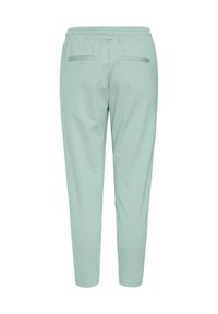 Ljusgröna joggerbyxor med elastisk midja, två bakfickor och en tapered ben-design. Tillverkade av ett mjukt tyg med en slät textur.