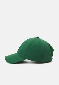 Grønn caps laget av bomull med forsterket brem, seks-panel design og luftelommer. Har en sydd logo-merke på siden.