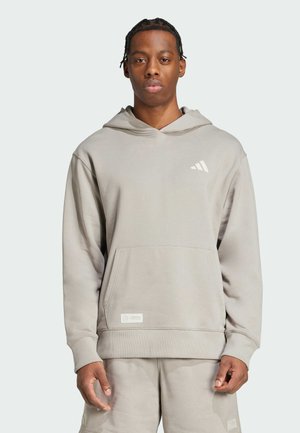 Grå huvtröja i mjukt material, med en framficka, ribbade ärmslut och en liten vit logotyp på bröstet.