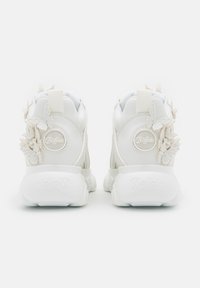 Paire de baskets blanches Buffalo vues de dos avec des appliques papillon 3D décoratives sur les côtés.