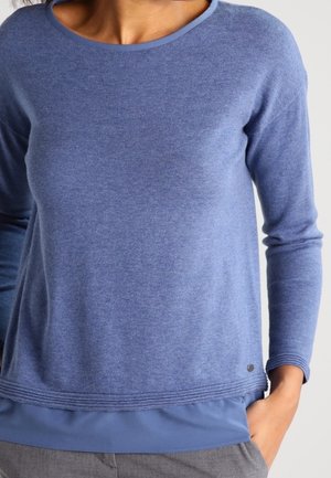 Blauwe lange mouwtrui van een zachte brei. Met een ronde hals, geribbelde zoom en een gelaagd uiterlijk met een zijdeachtige onderrand.