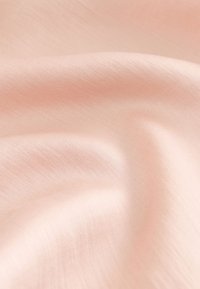 Mīksts, gaiši rozā audums ar gludu faktūru, kas izstaro maigu spīdumu un smalkas locījumu līnijas. Materiāls šķiet viegls un plūstošs.