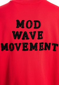 Sudadera roja con letras negras texturizadas que dicen "MOVIMIENTO MOD WAVE", con cuello redondo y detalles de costura visibles.
