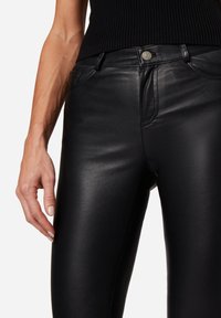 Svarta fusk läderbyxor med slim fit, som har en framknapplåsning, fickor och en slät, glänsande yta.
