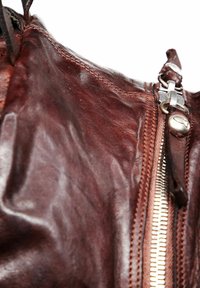 Borsa in pelle marrone con superficie texture, dotata di una zip argento prominente e un tirante in pelle. Dettagli di cucitura sottili visibili.