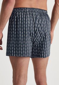 Boxershorts in marineblauwe stof met een herhalend wit en lichtgroen patroon. Elastische tailleband met een losse pasvorm.