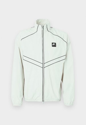 Λευκός ελαφρύς μπουφάν με ψηλό γιακά, μαύρο φερμουάρ και κεντημένο λογότυπο. Διαθέτει μαύρη τρέσα και ελαστικά μανίκια για εφαρμοστή εμφάνιση.