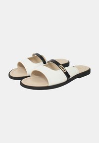 Infradito bianchi con una fascia in vernice nera, suola piatta e design aperto sul davanti. Presenta un logo in tonalità oro sulla fascia.