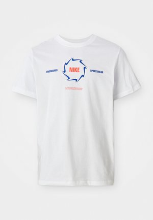 Valge lühikeste varrukate Nike T-särk, millel on sinine swooshi ring ja punane "NIKE" tekst, lisaks sinine "ENGINEERED SPORTSWEAR" ja väike punane loosung all.