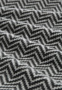 Grijs en zwart visgraatpatroon stof met een zachte, gestructureerde oppervlakte, die zigzaglijnen en een geweven uitstraling toont.