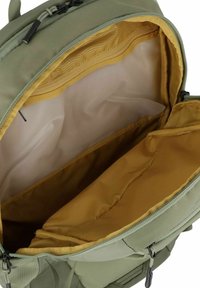 Sac à dos vert olive avec un intérieur jaune, doté d'une ouverture zippée et de plusieurs compartiments pour l'organisation et le rangement.